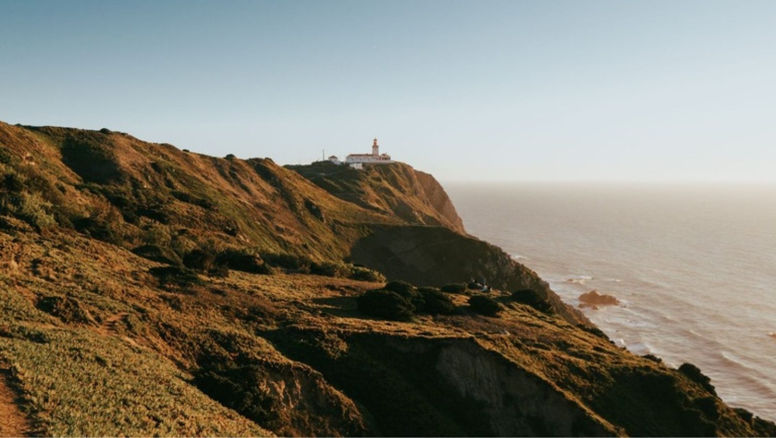 Lighthouse on the cliffs of Cabo da Roca in warm evening light above the Atlantic Ocean, Portugal